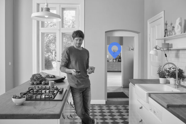 Man using smartphone and holding bell pepper in kitchen